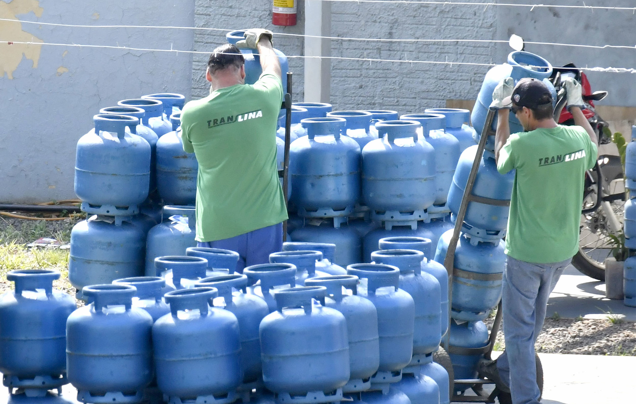 trabalhadores descarregam e organizam botijões de gás de cozinha
