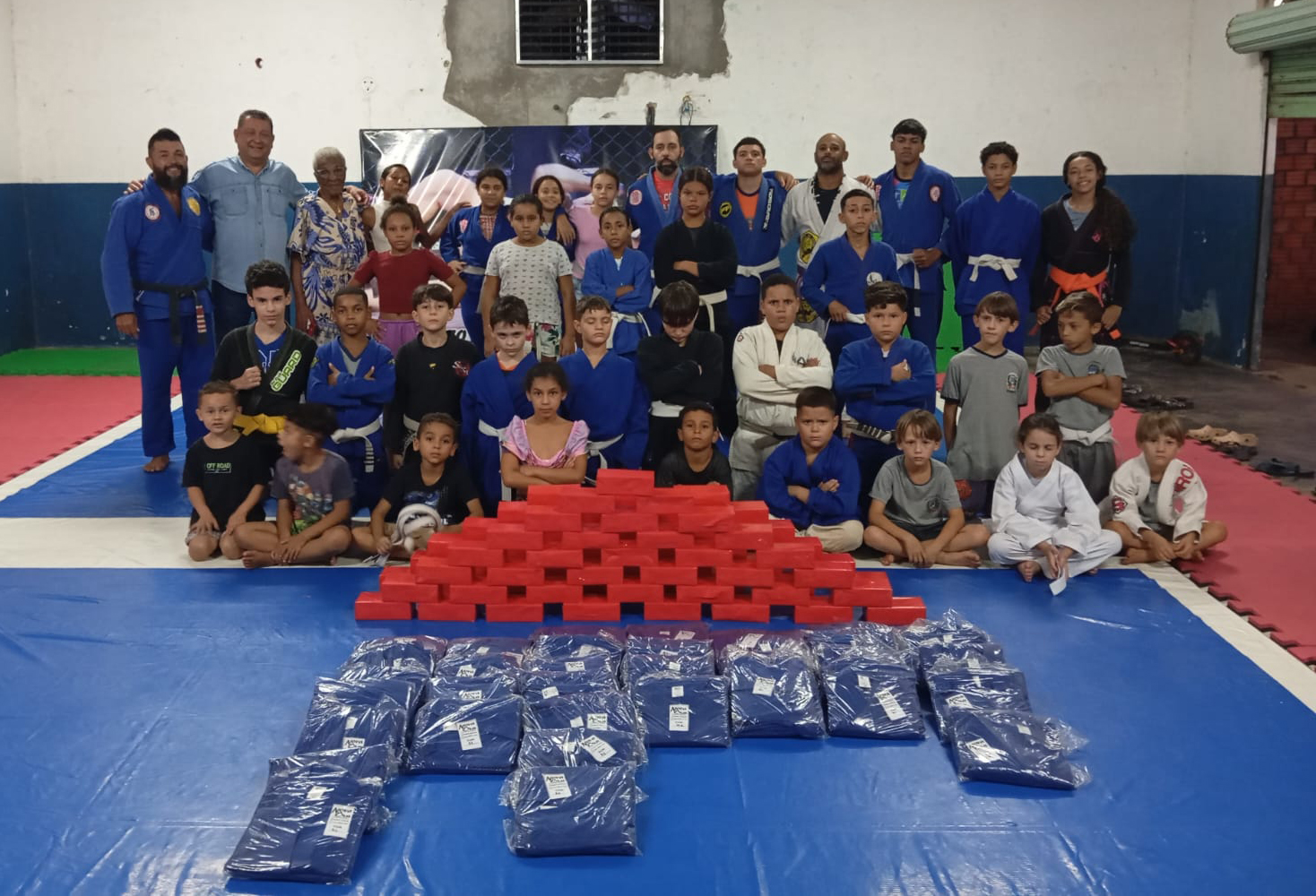 crianças alunas do projeto de jiu-jitsu, com instrutores e autoridades, recebendo os quimonos