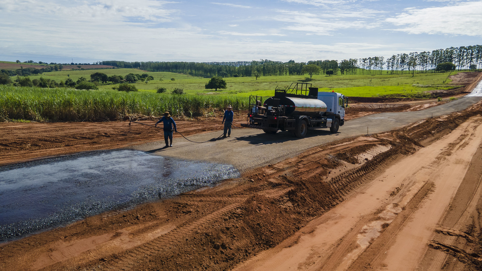 trabalhadores fazem a pintura de ligação no leito da estrada