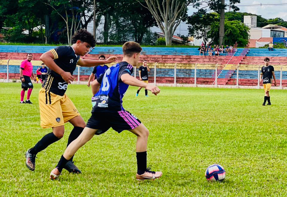 alunos atletas disputam bola no campo de futebol