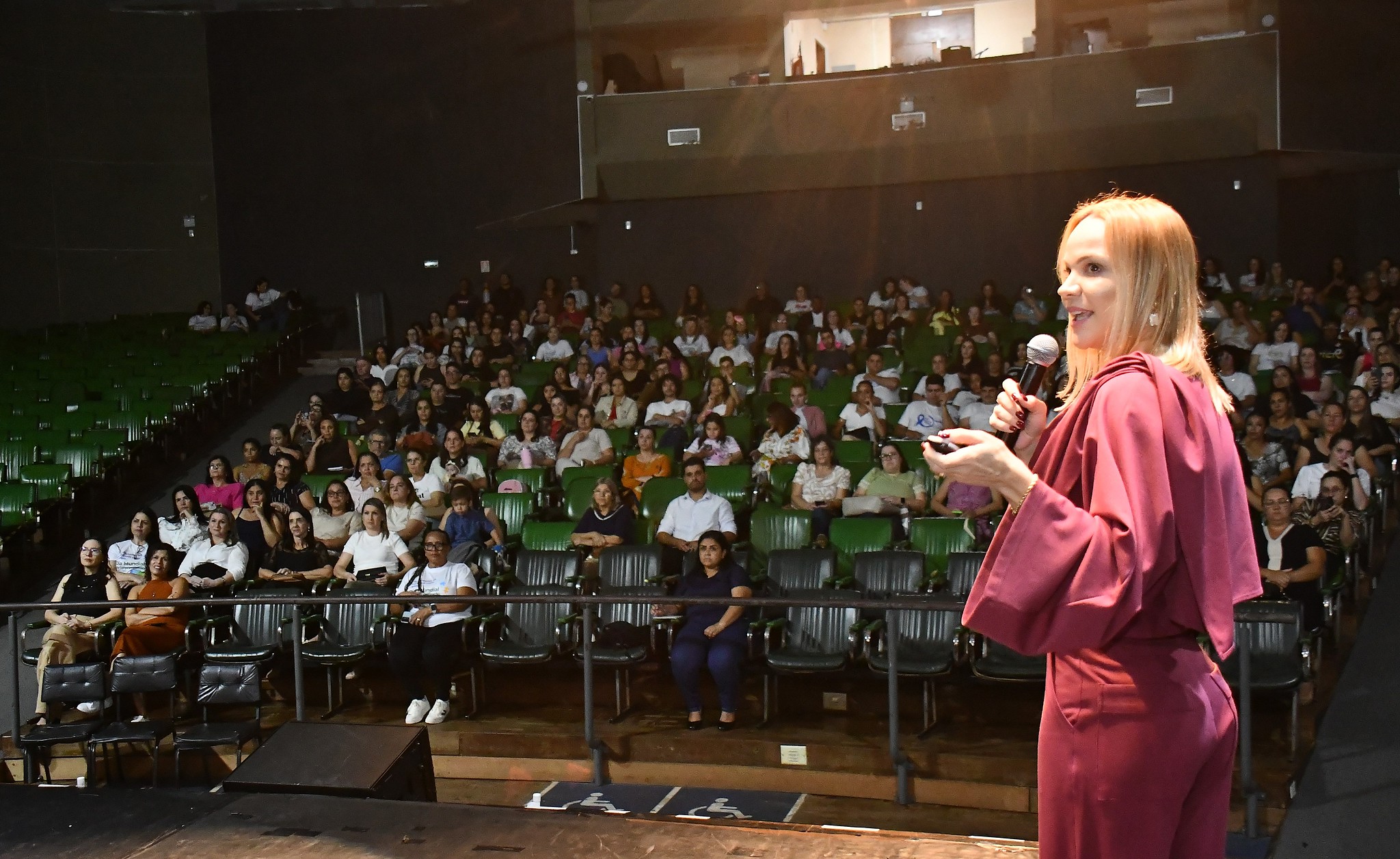 palestrante fala ao público no palco do teatro