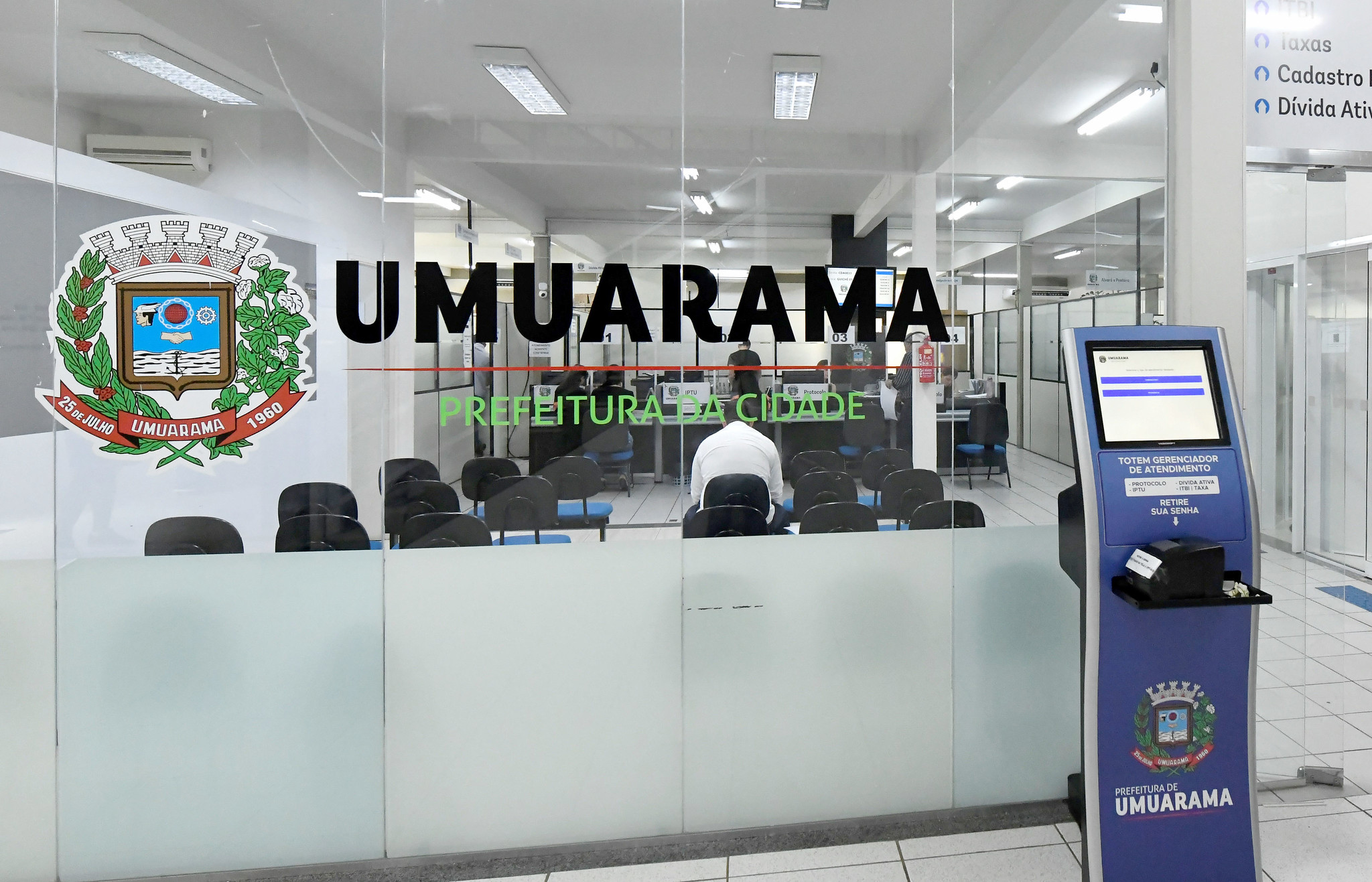 parede de vidro com brasão e o nome do município em destaque