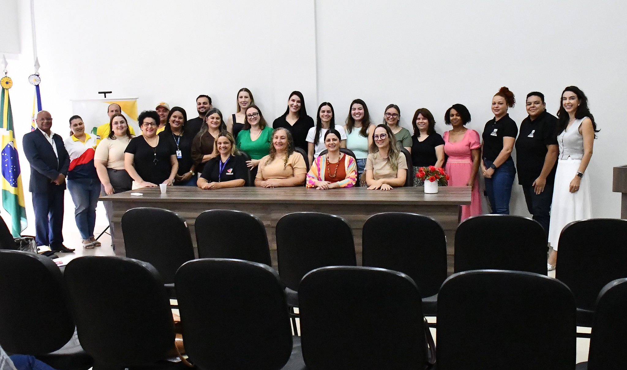 vários homens e mulheres posam para foto em volta de uma mesa