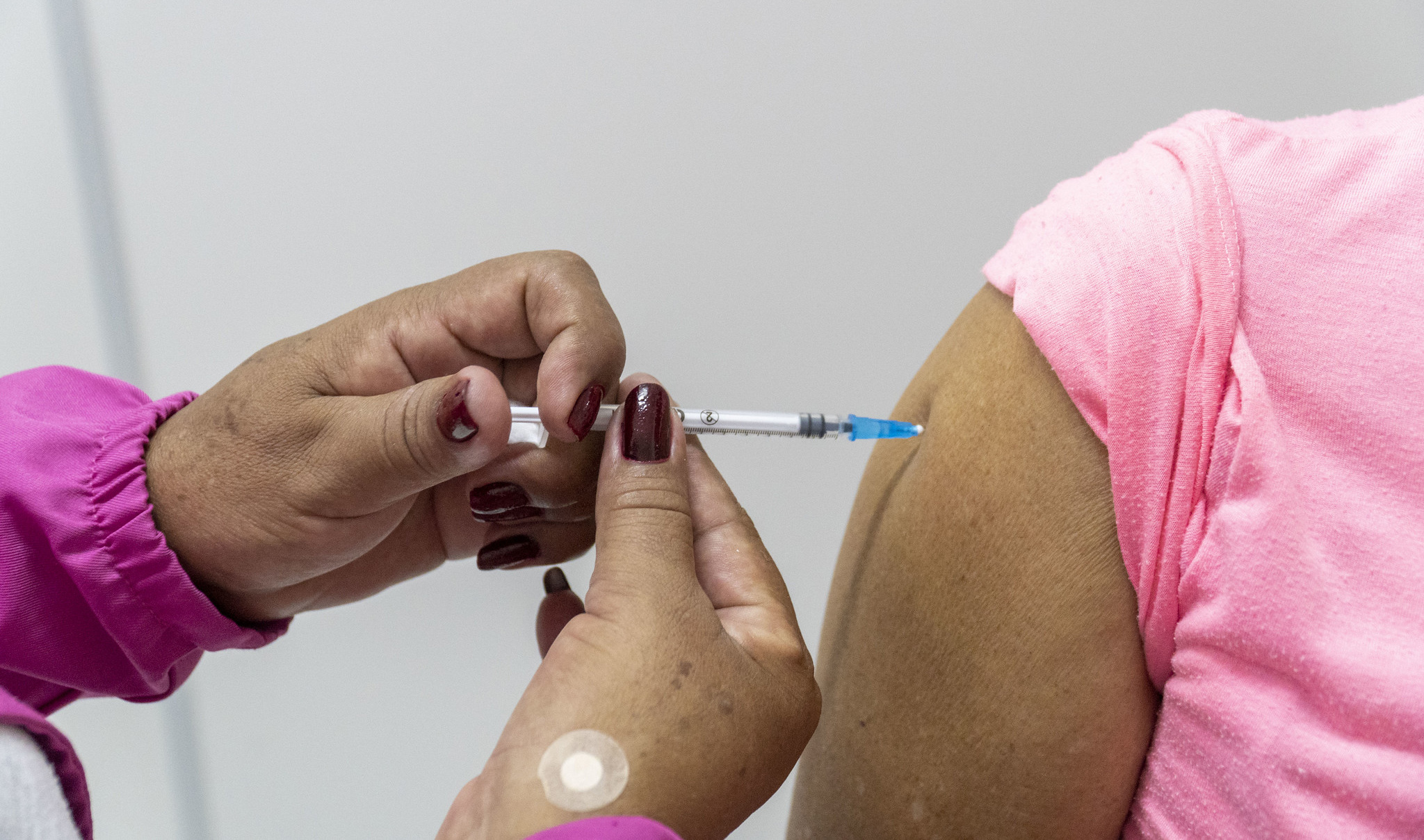 imagem de braço de uma mulher recebendo a vacina injetável contra a gripe