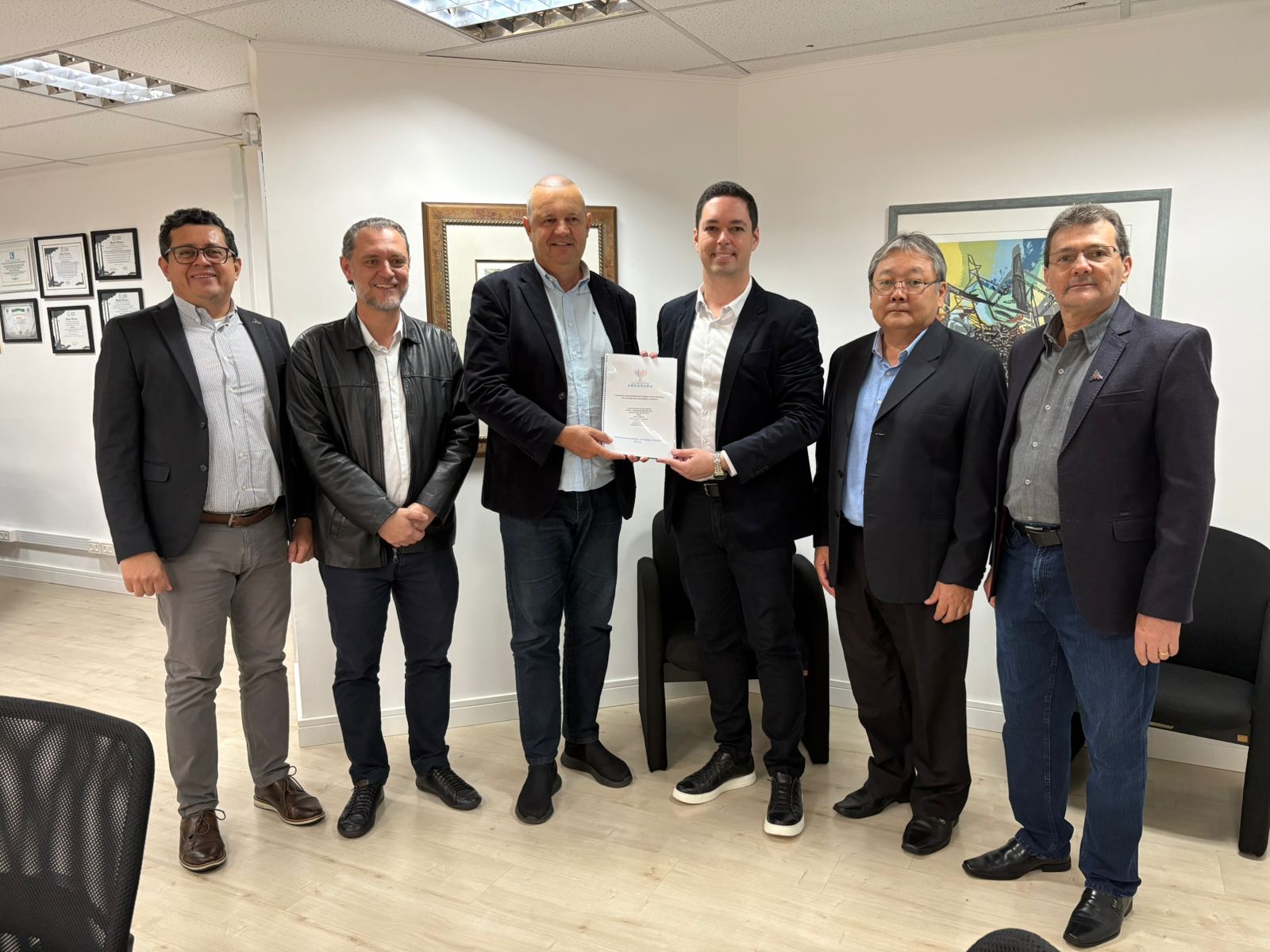 autoridades em pose na foto exibem o convênio que foi assinado