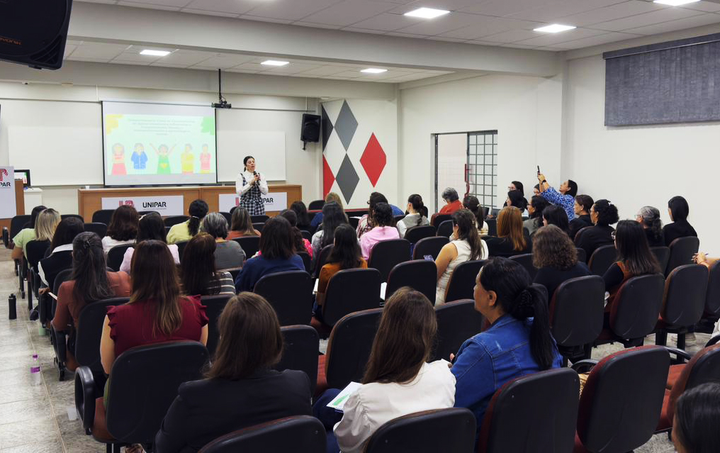 professoras participam de palestra, acomodadas em auditório