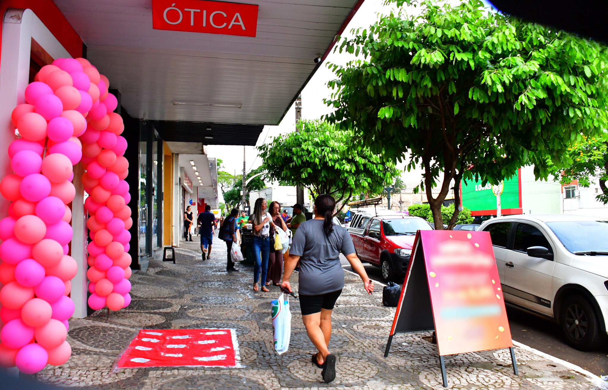 imagem de consumidores transitando pela calçada em avenida central da cidade