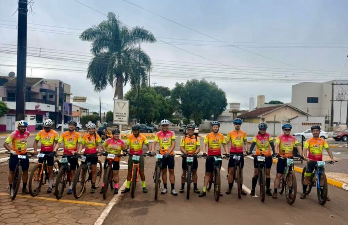 equipe de ciclismo posa para foto com atletas perfilados sobre as bicicletas