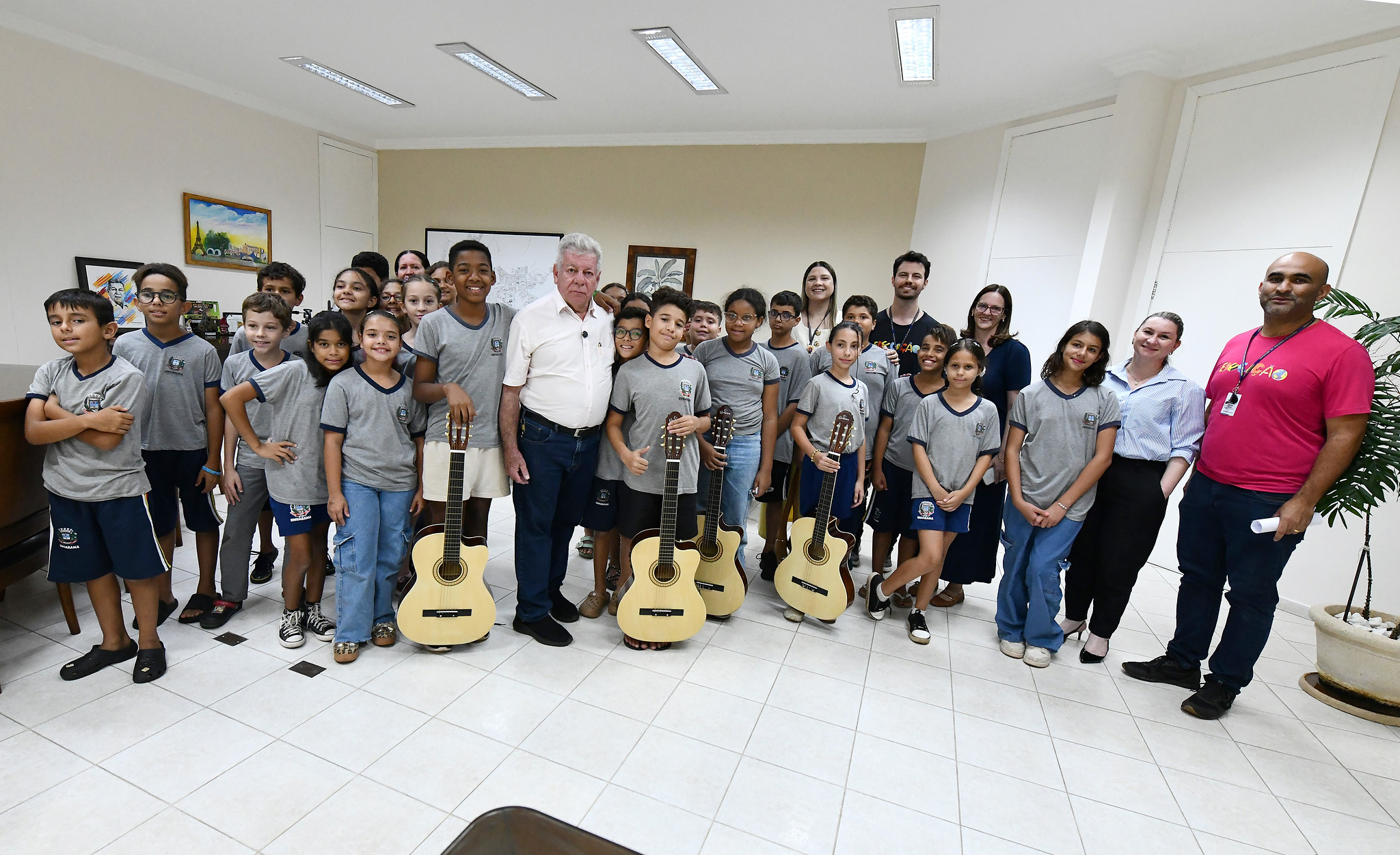 prefeito com alunos e professores em pose para foto no gabinete