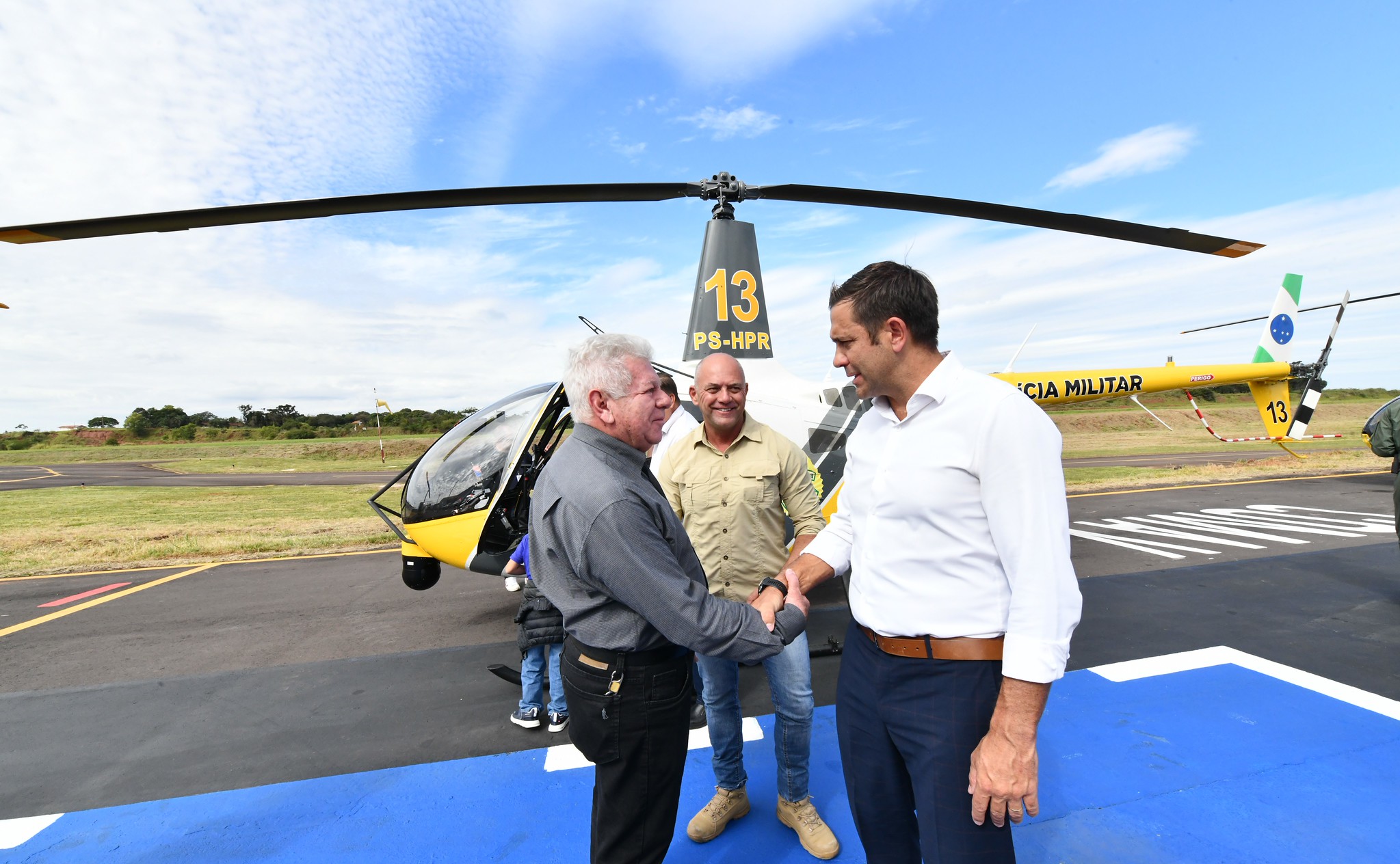 prefeito cumprimenta secretário de segurança diante de helicoptero