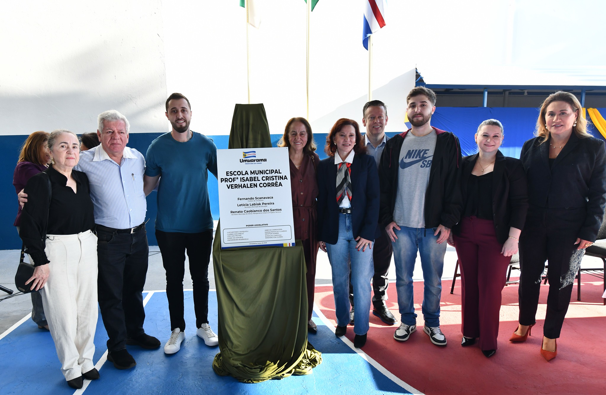 autoridades e familiares da professora homenageada ao lado da placa inaugural