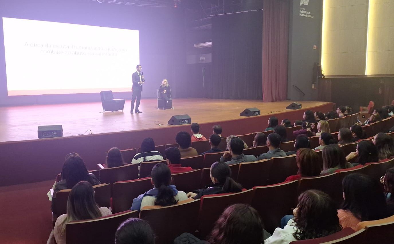 palestrante fala ao público no palco do teatro da unipar