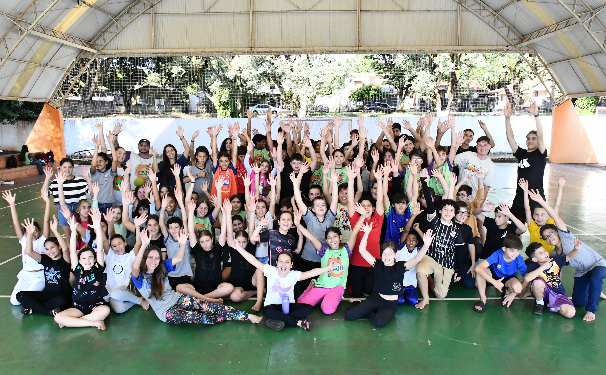crianças e adolescentes posam para foto na quadra de esportes do centro da juventude