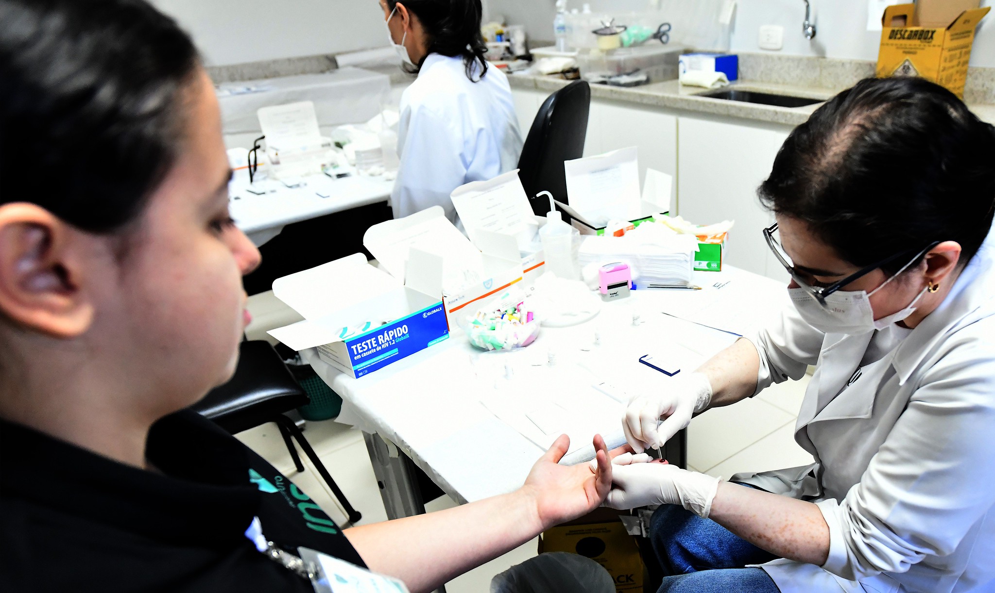 mulher realiza coleta de sangue para teste rápido com enfermeira
