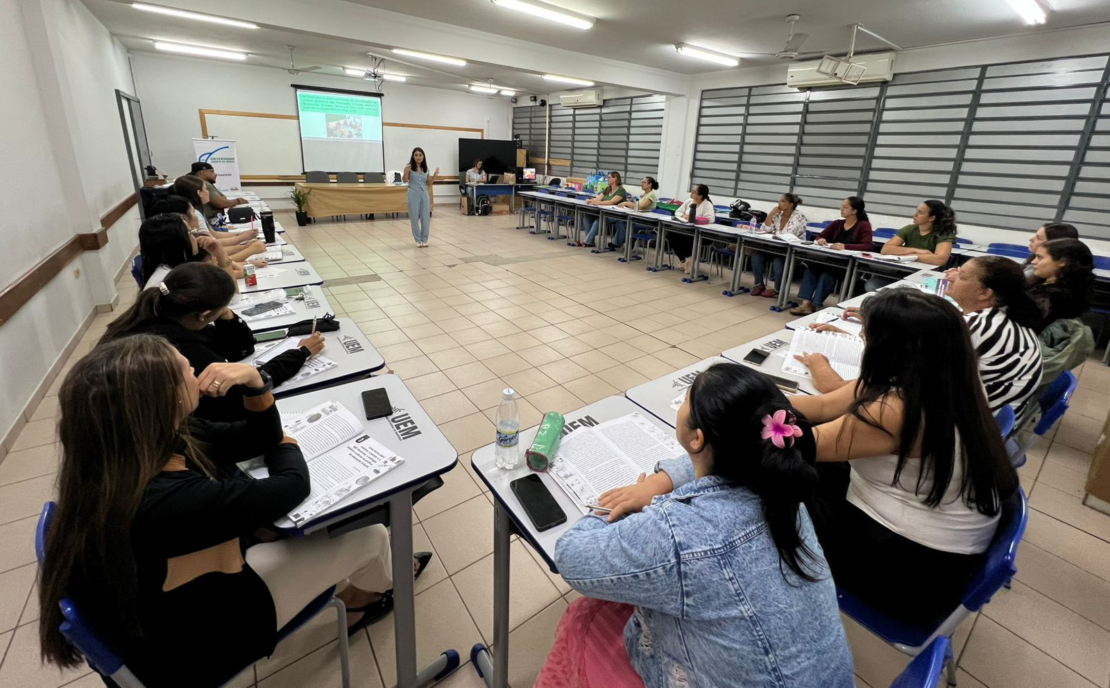 sala de aula lotada de alunos adultos com carteiras em 'U'