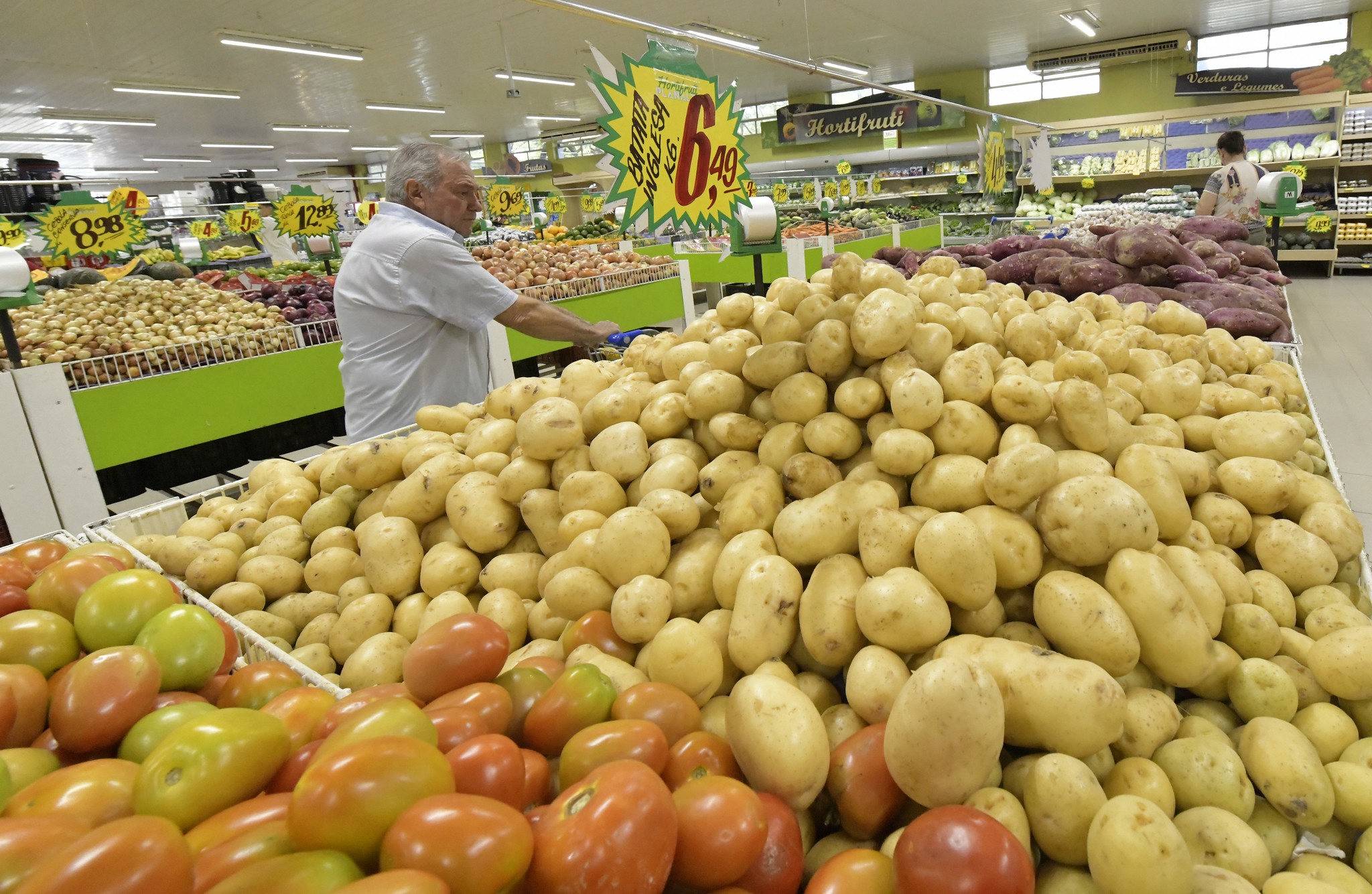 banca com batata em supermercado e consumidor observando preço
