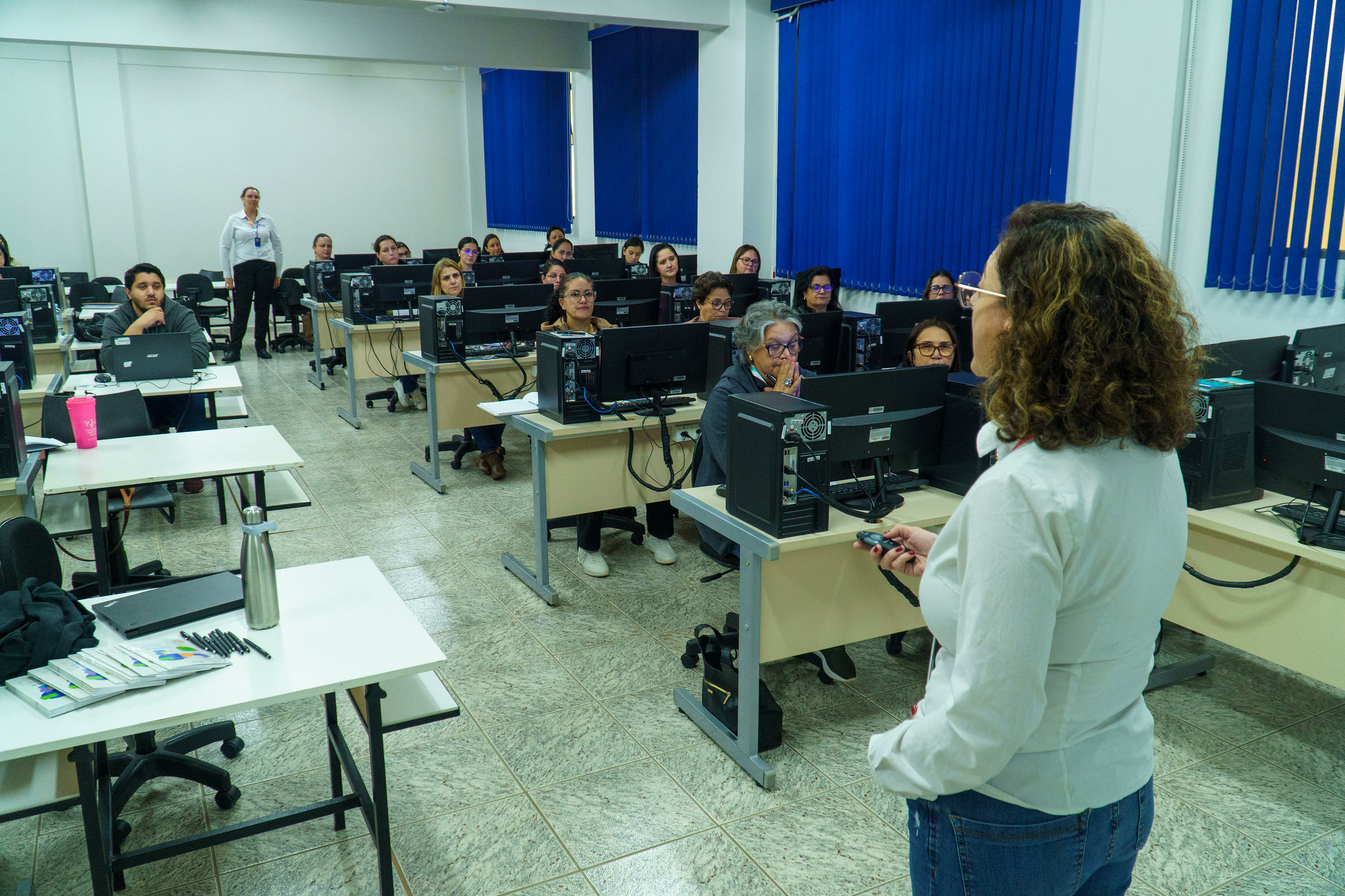 instrutora fala aos participantes do curso em sala de informática