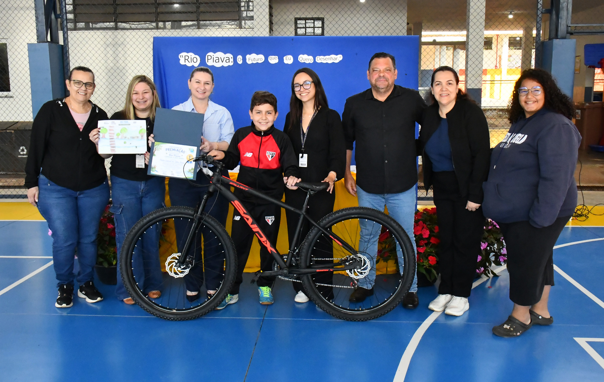professores, secretários e o aluno vencedor com a bicicleta