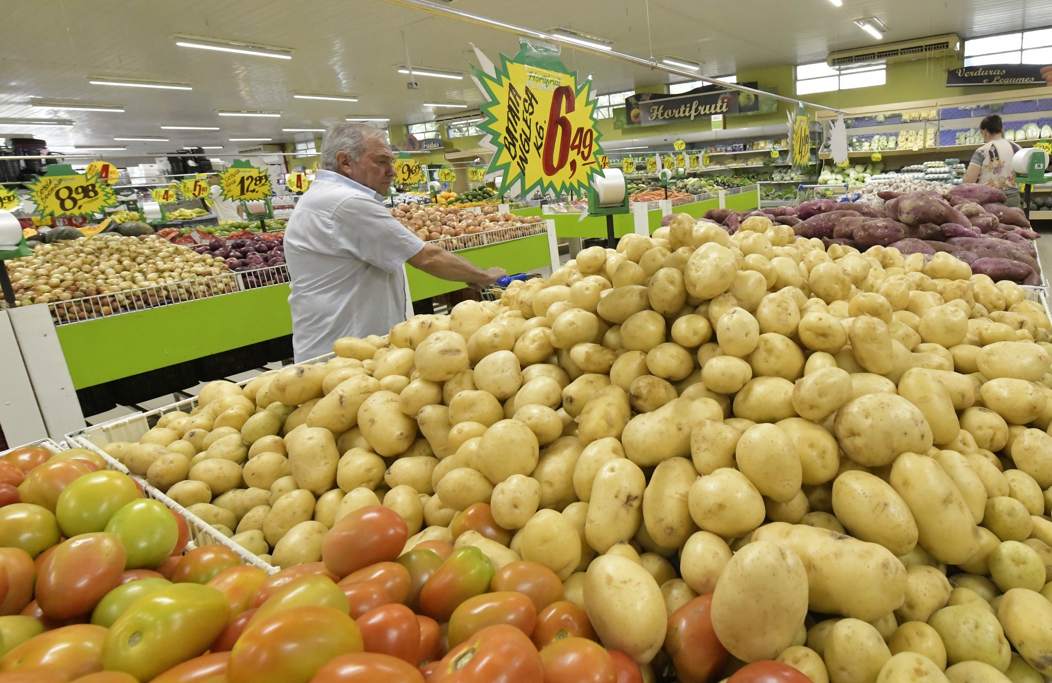 consumidor diante de uma banca com batatas em supermercado