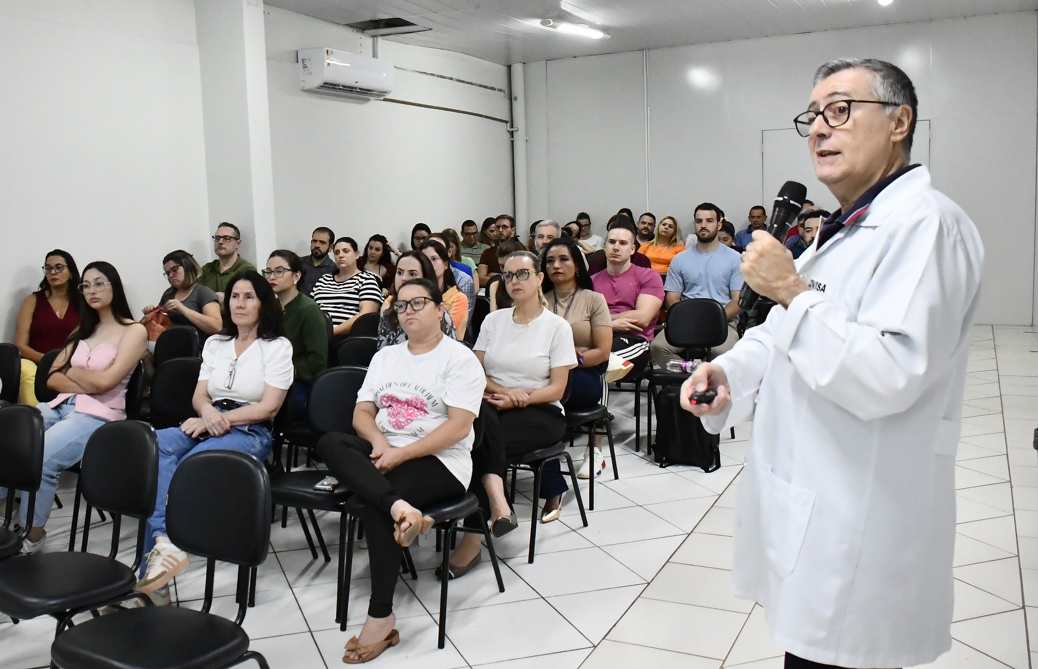 imagem do médico palestrante falando ao público sentado no pequeno auditório