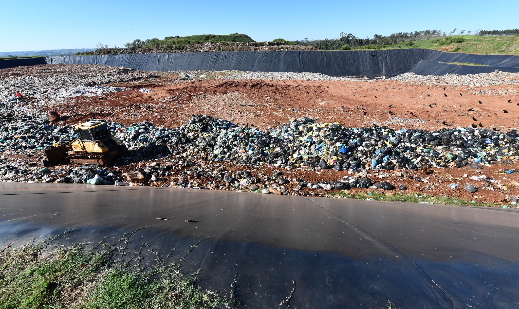 trator espalha resíduos orgânicos dentro de vala no aterro sanitário