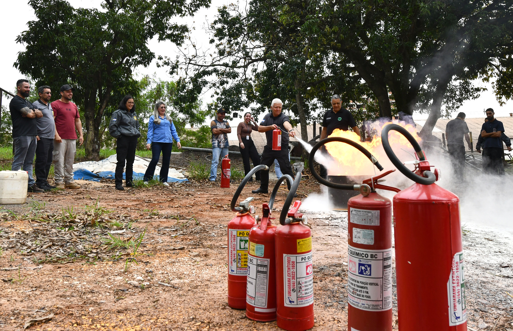 participante do curso usa extintor para apagar incêndio e demais pessoas observam