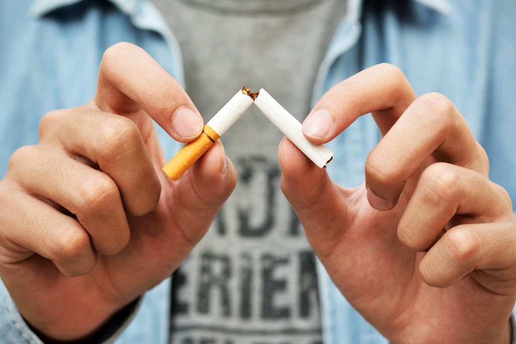 imagem de mãos humanas segurando cigarro quebrado ao meio