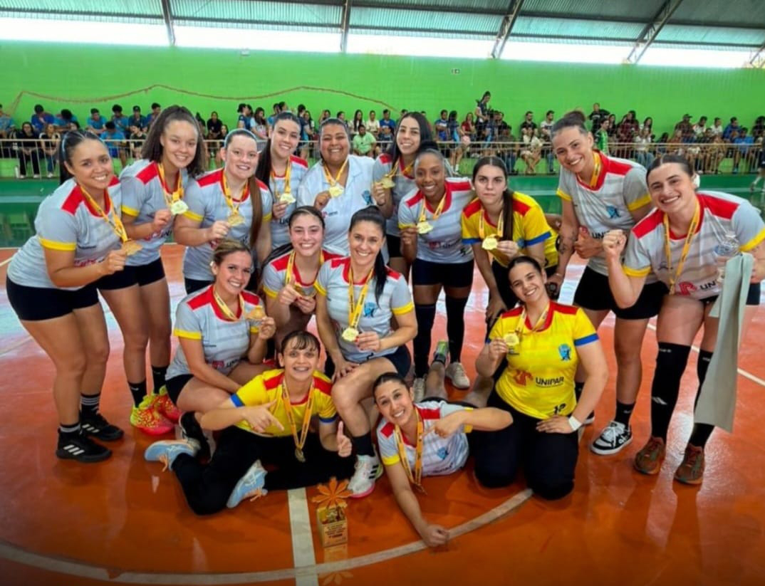 atletas da equipe de handebol feminino na quadra, com medalha