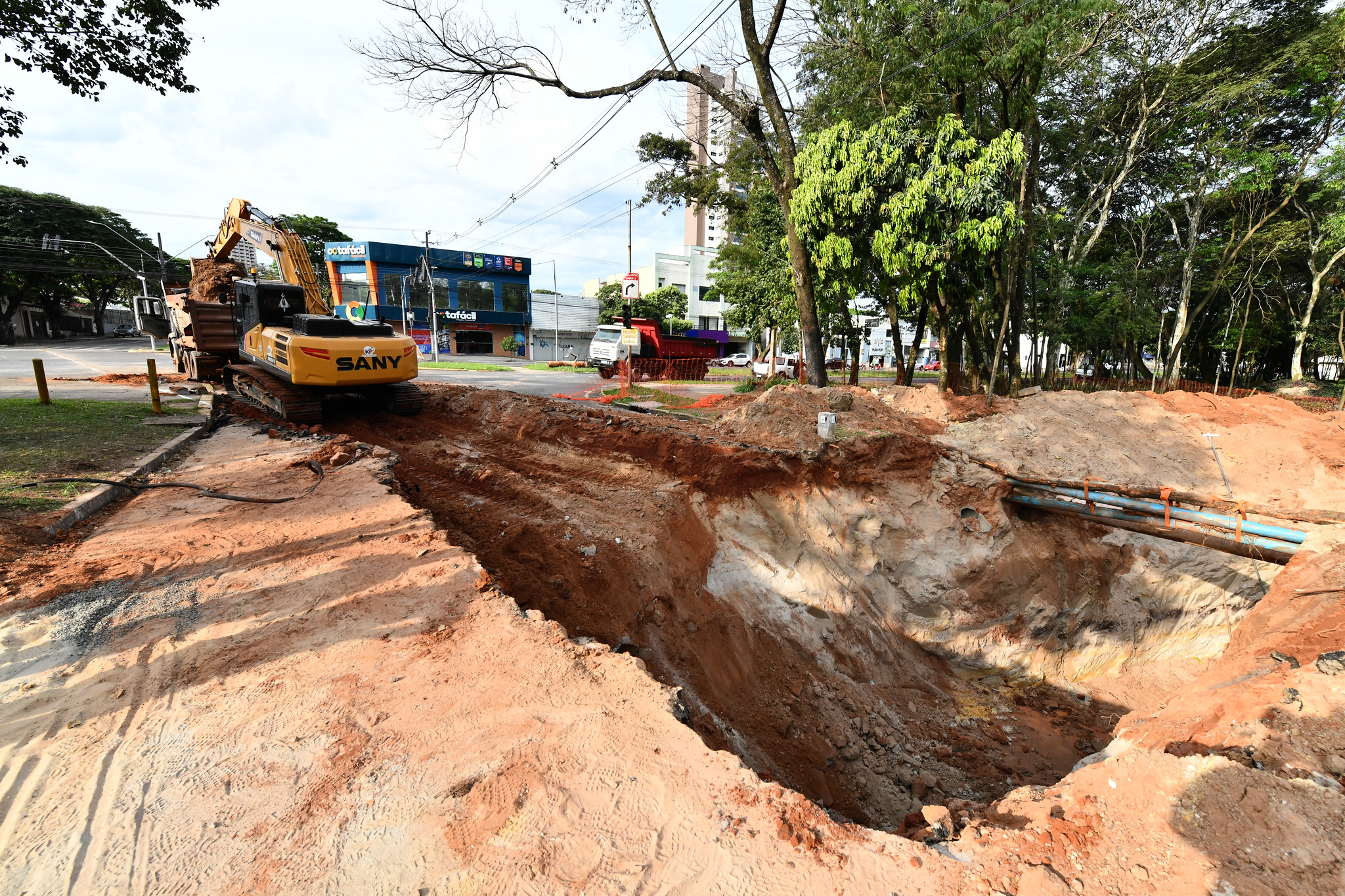 escavadeira saindo de escavação carrega caminhão com terra