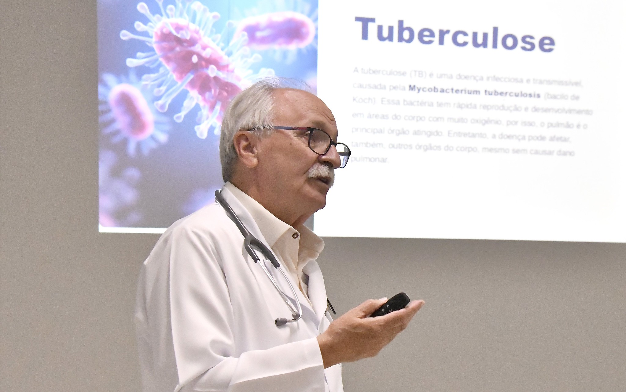 imagem do médico palestrante falando diante de um painel