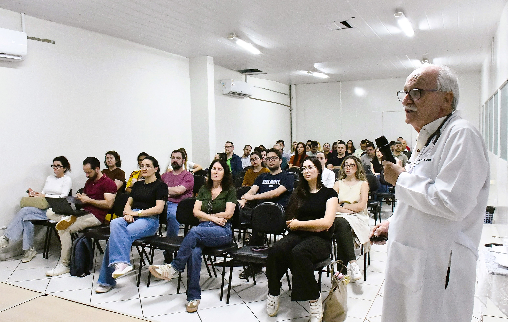 médico fala para o público sentado no auditório