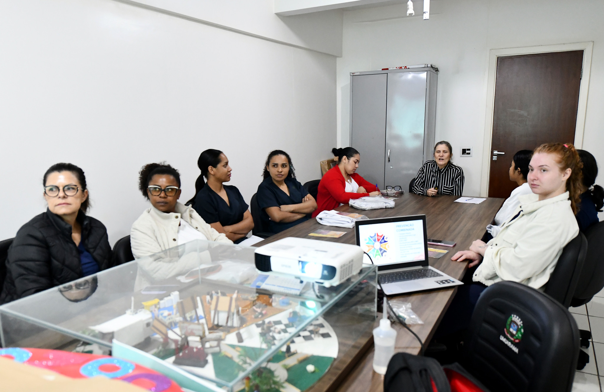 pessoas reunidas em torno de uma mesa com computador e anotações
