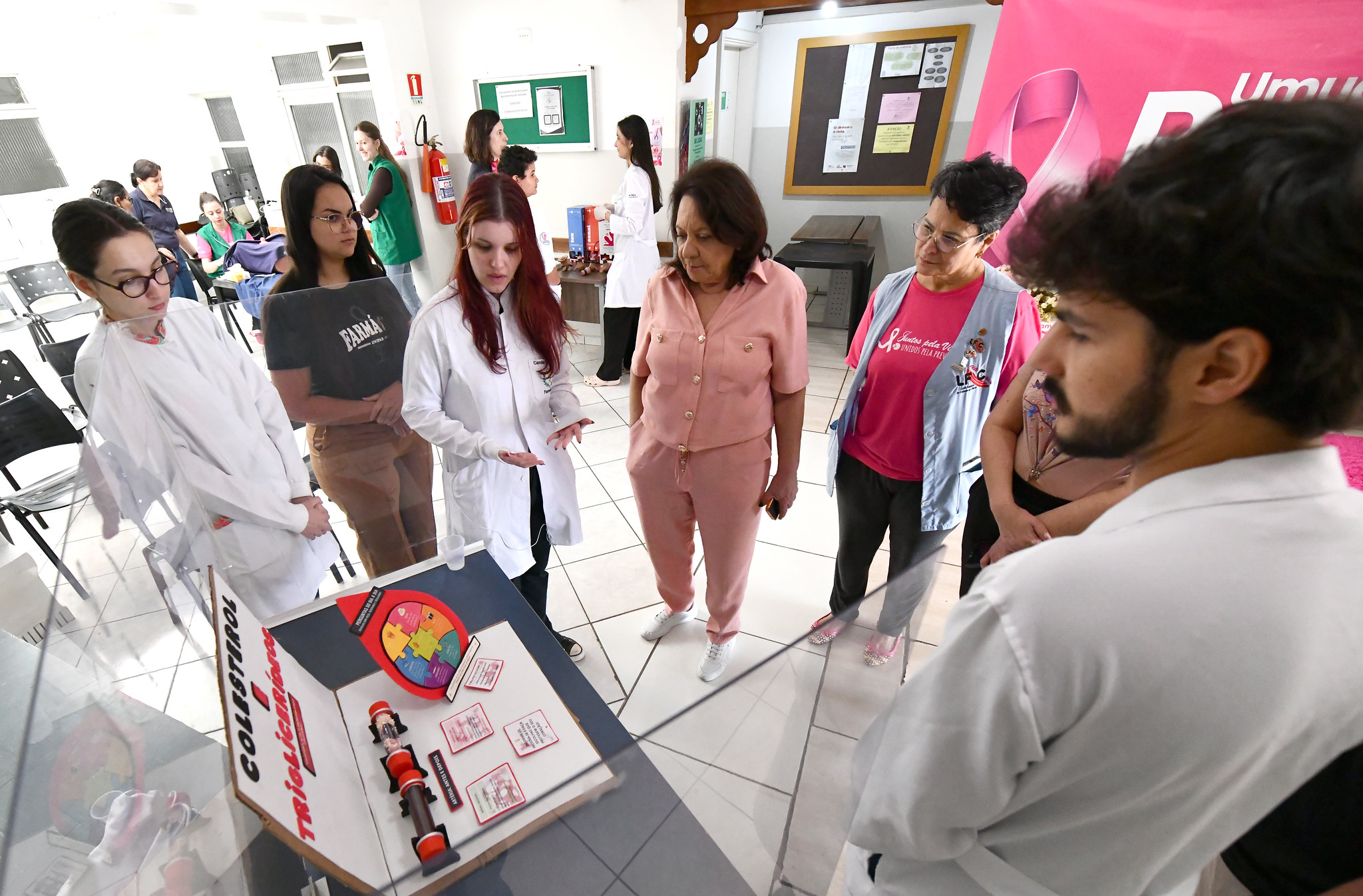 pessoas observam explicação de estudantes sobre colesterol