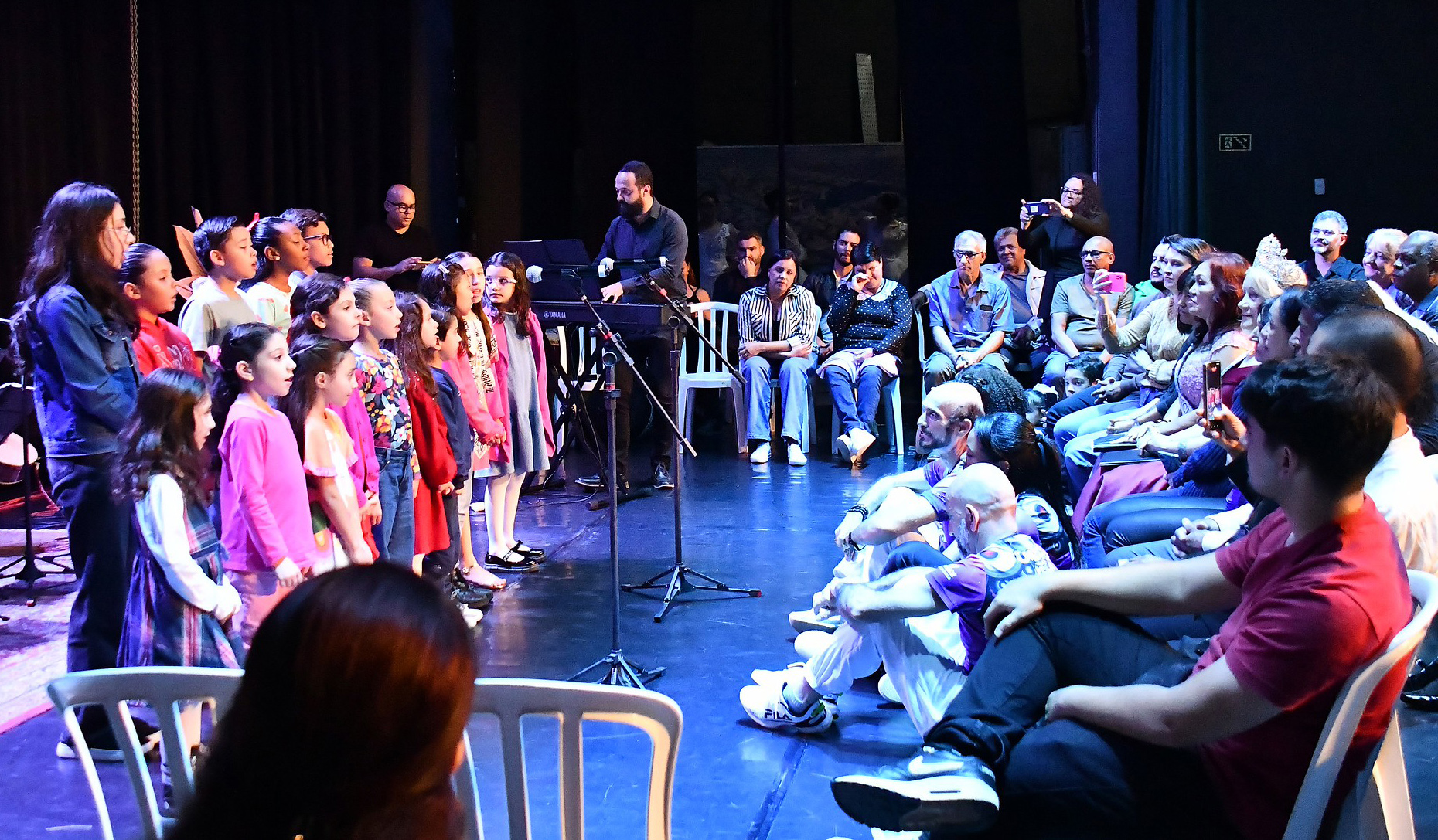 crianças cantam para o público no sarau cultural