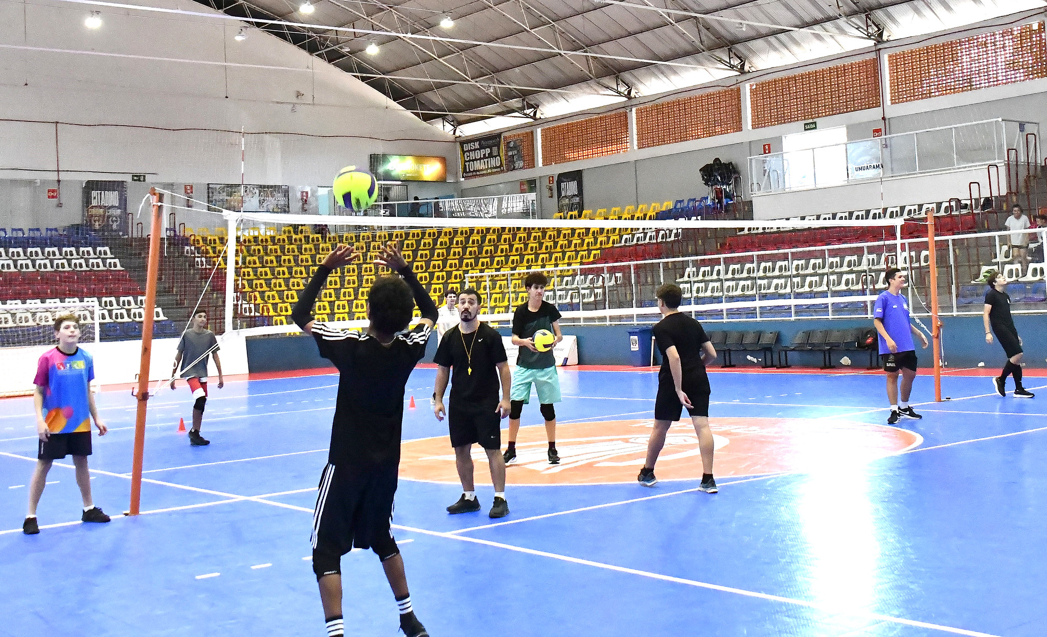 atletas treinam vôlei em quadra esportiva