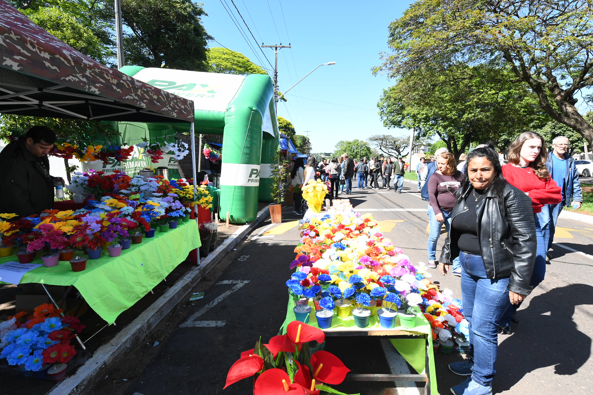 pessoas em bancas de venda de flores na frente do cemitérios
